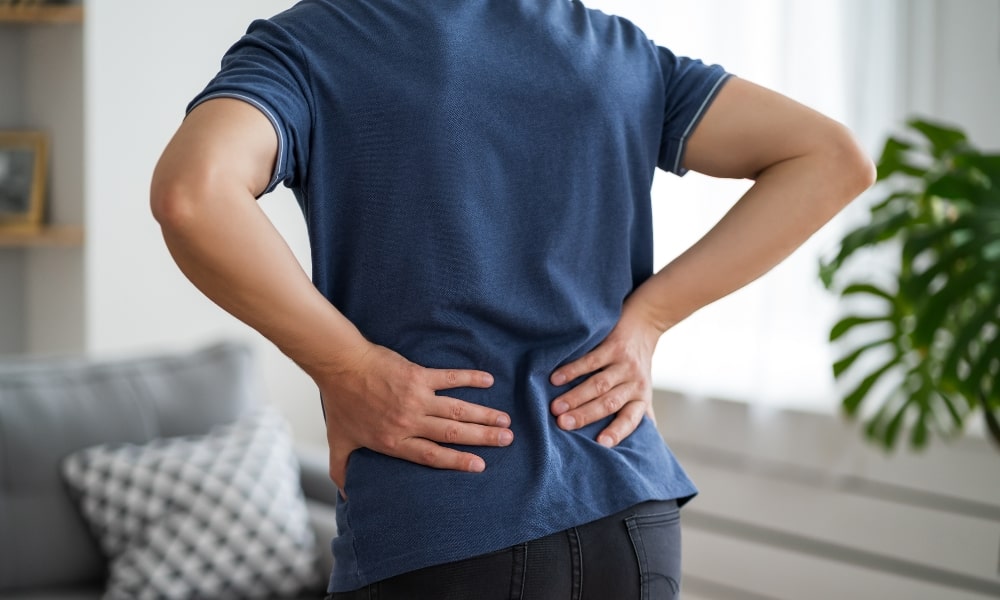 腰痛で腰に手を当てる男性